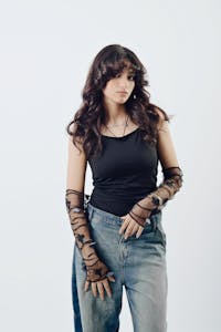 Stylish portrait of a young woman in fashionable lace gloves and casual attire.